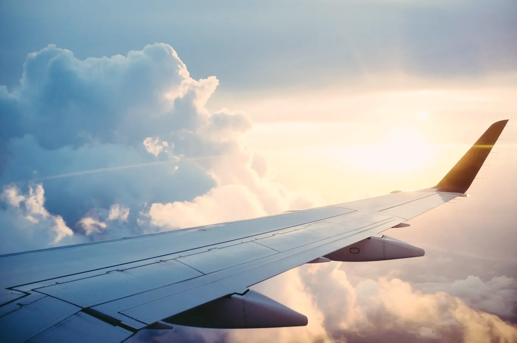 Aircraft wing above golden-hour clouds